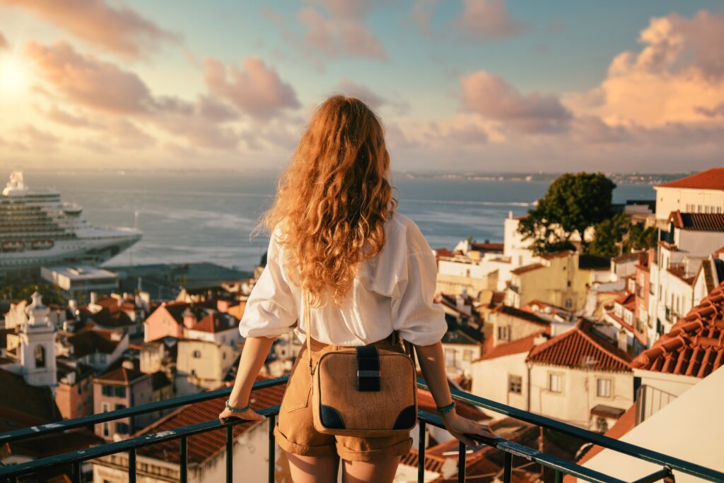 Young female standing on a platform surrounded by fences and observing Lisbon at daytime in Portugal